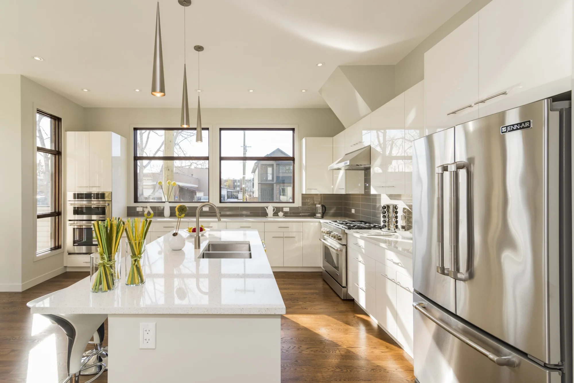 Bright kitchen with white gloss cabinets, a quartz island and stainless steel appliances